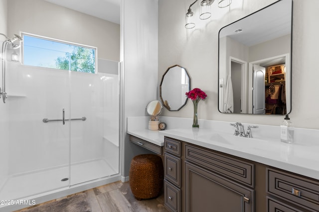 full bathroom featuring wood finished floors, vanity, and a shower with door