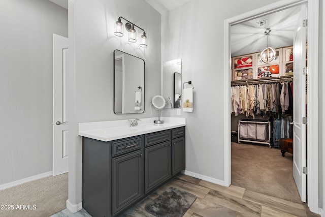 bathroom featuring visible vents, vanity, baseboards, and a spacious closet