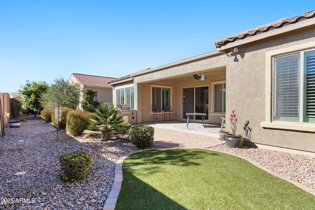 back of property featuring ceiling fan, fence, a tiled roof, and stucco siding