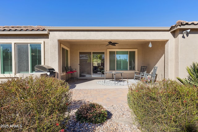 exterior space with a ceiling fan, a patio, a tiled roof, and stucco siding