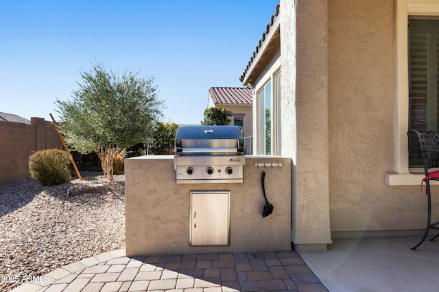 view of patio with exterior kitchen, a grill, and fence