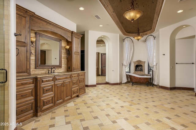 bathroom with vanity, separate shower and tub, and a raised ceiling