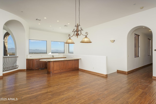 kitchen with kitchen peninsula, a chandelier, hanging light fixtures, and dark hardwood / wood-style floors