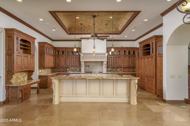 kitchen with decorative backsplash, pendant lighting, a tray ceiling, and a large island