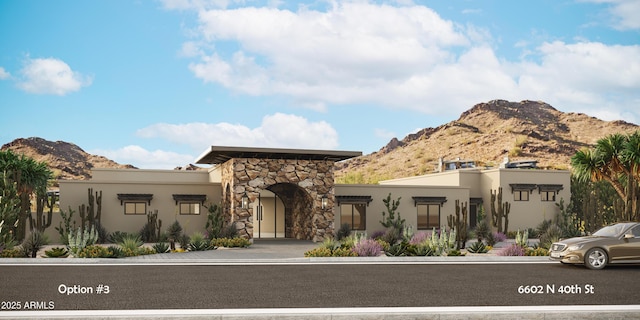 view of front of home with stone siding, a mountain view, and stucco siding