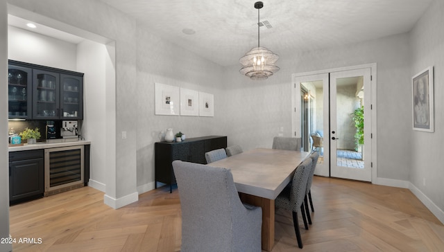 dining room with wine cooler, an inviting chandelier, and light parquet floors