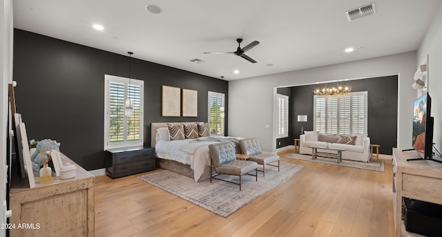 bedroom with ceiling fan with notable chandelier and light wood-type flooring