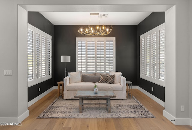 living room with a wealth of natural light, a notable chandelier, and light hardwood / wood-style floors