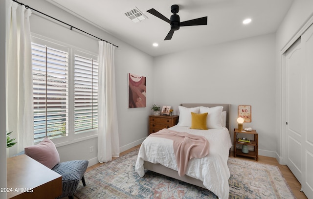 bedroom with light wood-type flooring, multiple windows, a closet, and ceiling fan