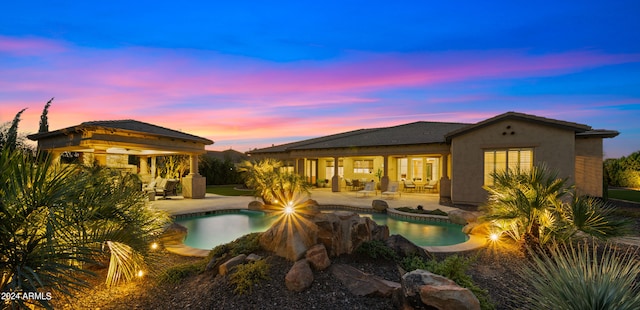 pool at dusk featuring a gazebo and a patio area