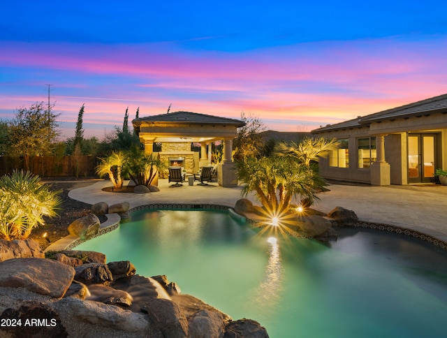 pool at dusk featuring a patio and a gazebo