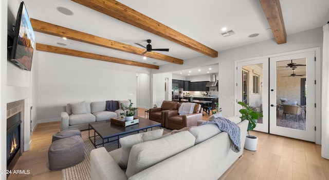 living room featuring french doors, light hardwood / wood-style floors, beam ceiling, and ceiling fan