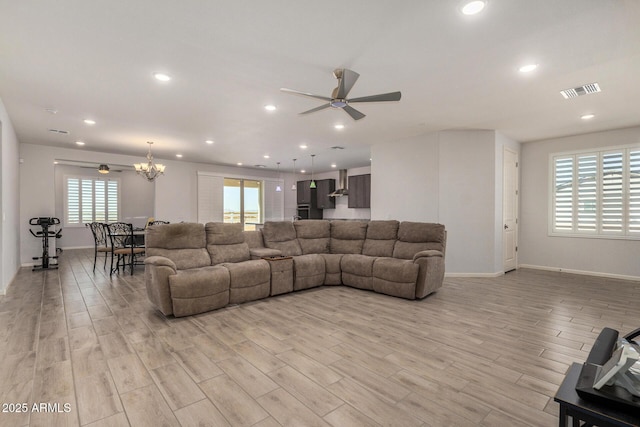 living room featuring light wood-type flooring and ceiling fan with notable chandelier