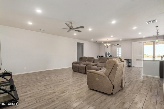 living room featuring ceiling fan with notable chandelier