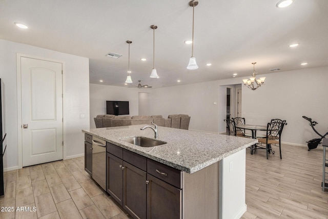 kitchen with light stone countertops, dishwasher, an island with sink, sink, and dark brown cabinets