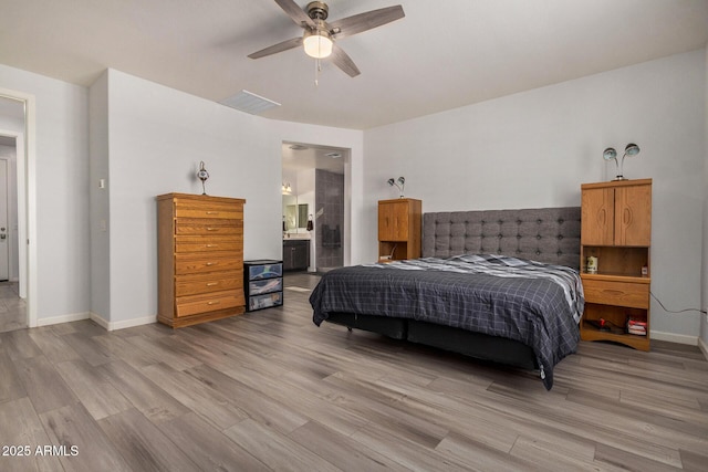 bedroom with light wood-type flooring, ceiling fan, and ensuite bath