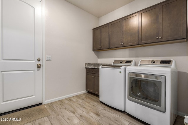 laundry room featuring washer and dryer, cabinets, and light hardwood / wood-style flooring