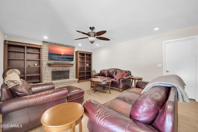 living room with ceiling fan, a fireplace, light wood-style flooring, and recessed lighting