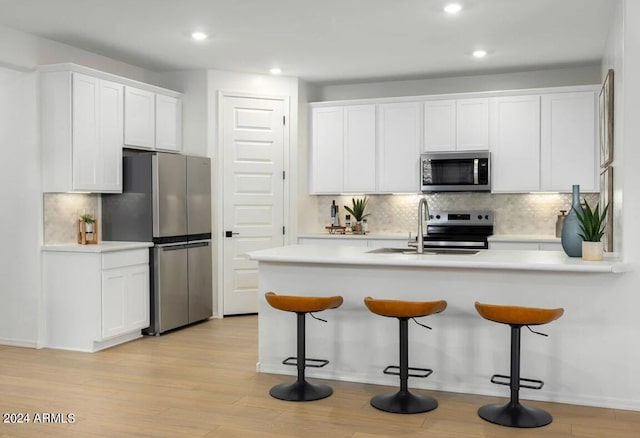 kitchen featuring light hardwood / wood-style flooring, white cabinetry, appliances with stainless steel finishes, and sink