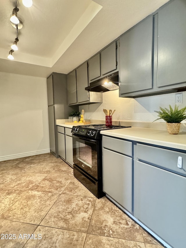 kitchen featuring under cabinet range hood, gray cabinets, light countertops, and gas stove