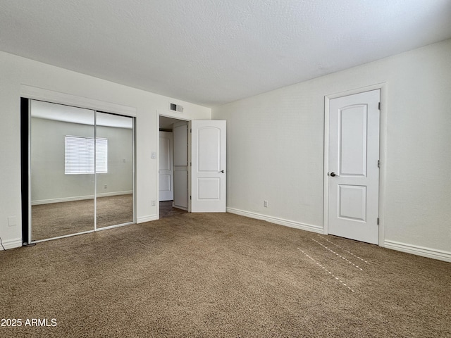 unfurnished bedroom with a textured ceiling, carpet floors, visible vents, baseboards, and a closet