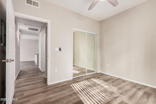 unfurnished bedroom with dark wood-type flooring, ceiling fan, and a closet