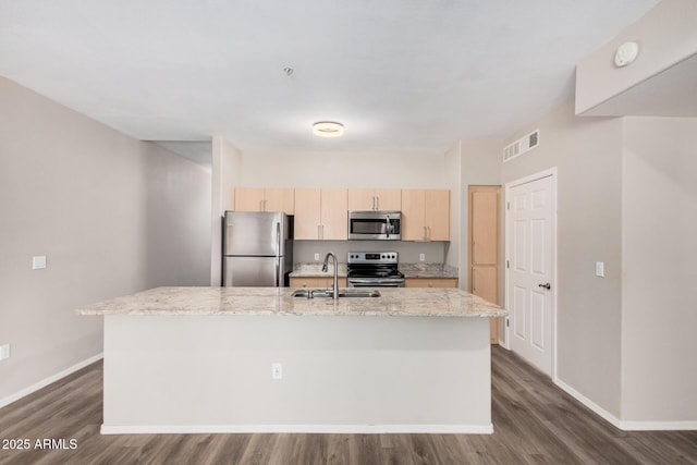 kitchen featuring sink, appliances with stainless steel finishes, light stone countertops, an island with sink, and light brown cabinetry