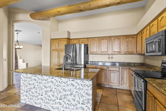 kitchen with appliances with stainless steel finishes, sink, dark tile patterned floors, a kitchen island with sink, and beam ceiling