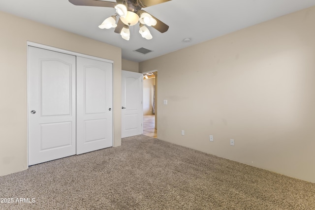 unfurnished bedroom with light colored carpet, ceiling fan, and a closet