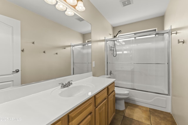 full bathroom featuring bath / shower combo with glass door, vanity, tile patterned floors, and toilet