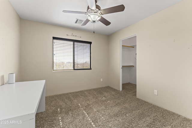 unfurnished bedroom with a spacious closet, a closet, ceiling fan, and carpet flooring