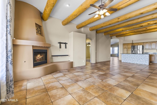 unfurnished living room featuring beam ceiling, ceiling fan, light tile patterned floors, and a fireplace