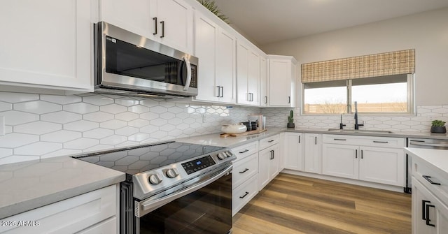 kitchen featuring sink, backsplash, white cabinets, and stainless steel appliances