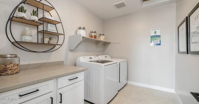 washroom featuring washing machine and dryer, cabinets, and light tile patterned floors