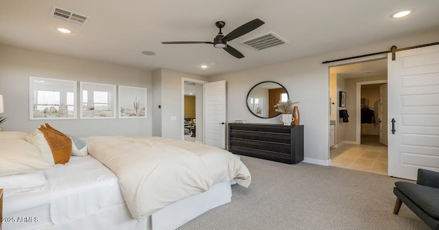 carpeted bedroom with ceiling fan, a barn door, and ensuite bathroom