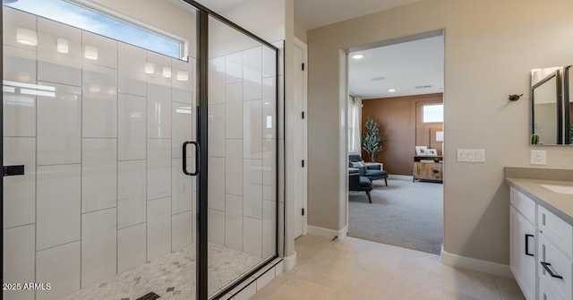 bathroom featuring a shower with shower door, vanity, and plenty of natural light