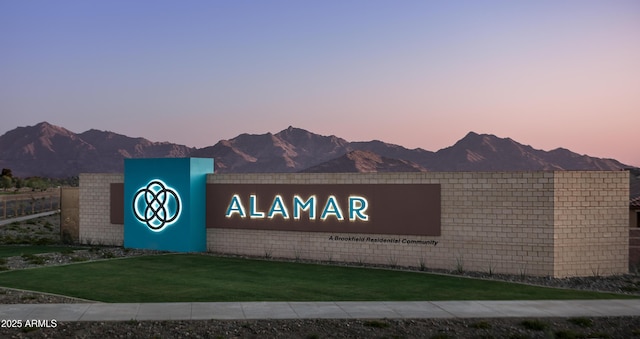 community / neighborhood sign with a lawn and a mountain view