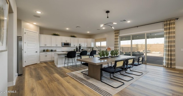 dining area featuring an inviting chandelier, light hardwood / wood-style flooring, and sink