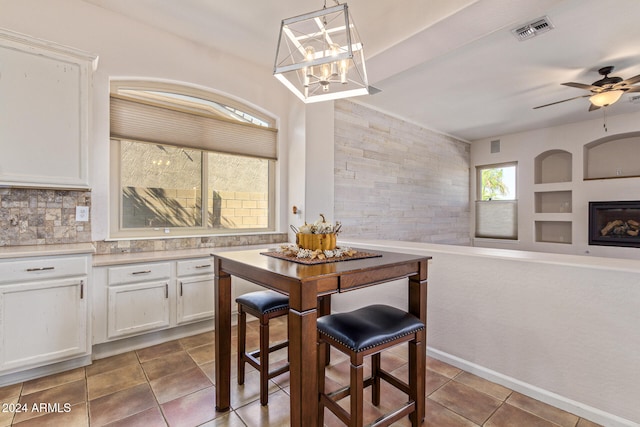 kitchen featuring ceiling fan with notable chandelier, pendant lighting, dark tile patterned floors, and white cabinets