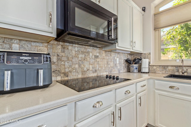 kitchen featuring white cabinets, tasteful backsplash, black appliances, and sink