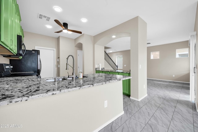 kitchen with visible vents, a peninsula, green cabinets, and a ceiling fan