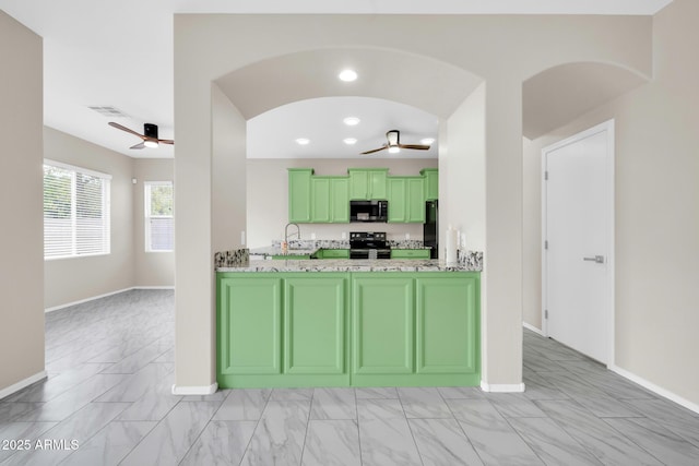 kitchen featuring arched walkways, marble finish floor, black appliances, a ceiling fan, and green cabinetry