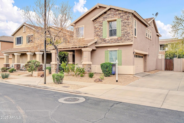 view of front of house featuring stucco siding, driveway, stone siding, an attached garage, and a gate