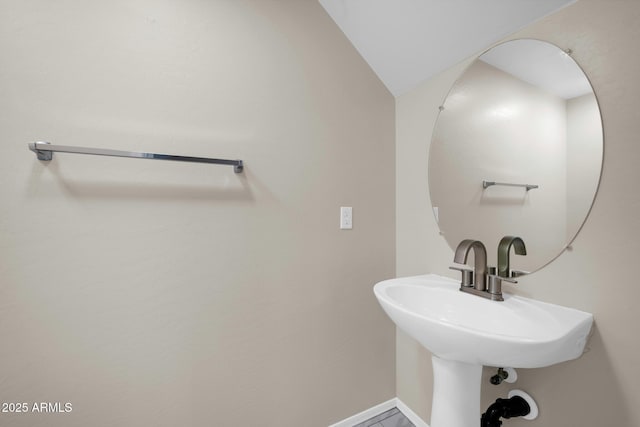 bathroom with lofted ceiling, baseboards, and a sink