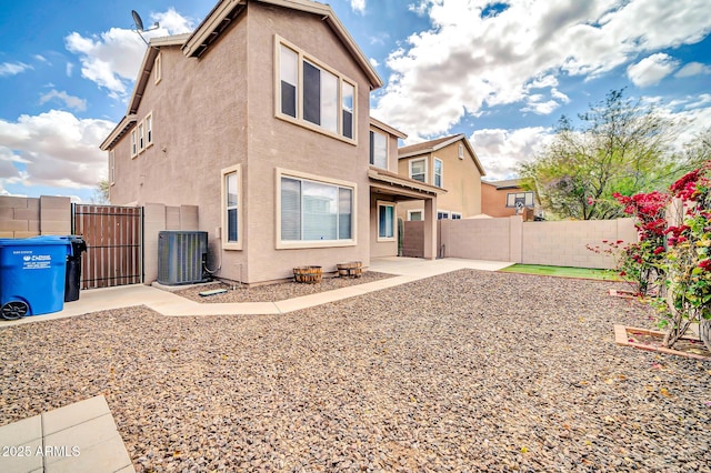 back of house with a gate, fence, central AC, and stucco siding