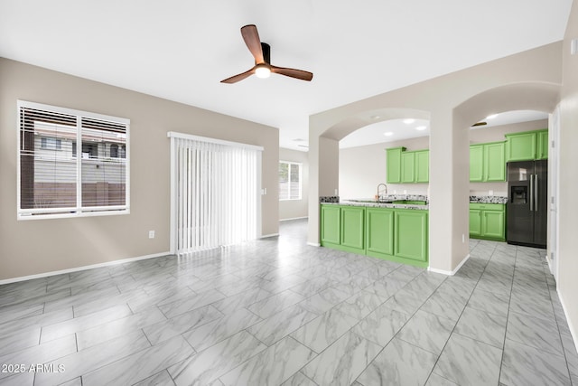 unfurnished living room with a ceiling fan, marble finish floor, and baseboards