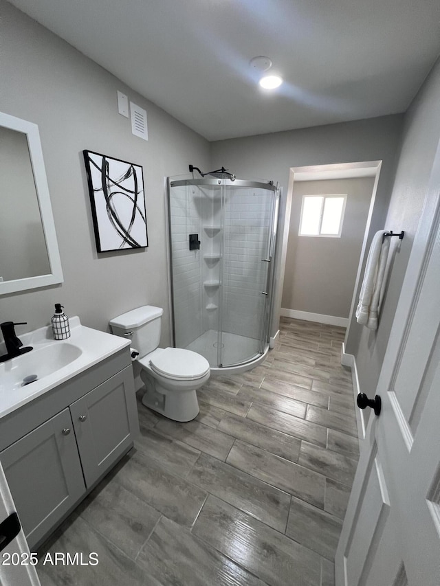 bathroom with walk in shower, vanity, and toilet