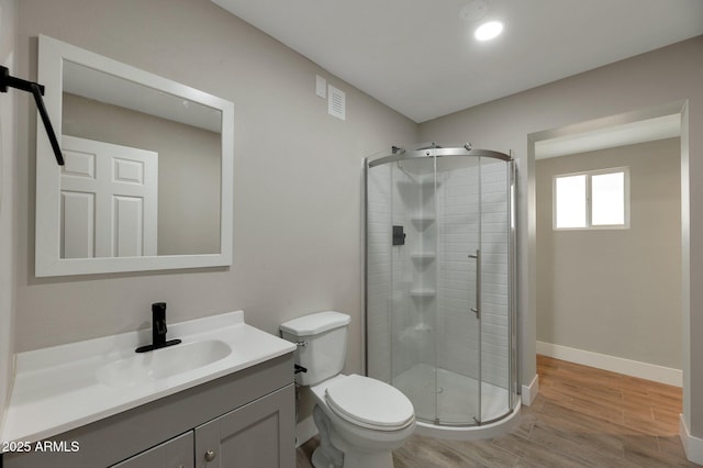 bathroom featuring a shower with door, vanity, wood-type flooring, and toilet