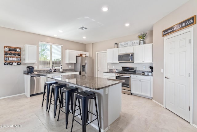 kitchen featuring sink, a breakfast bar area, appliances with stainless steel finishes, white cabinetry, and a center island