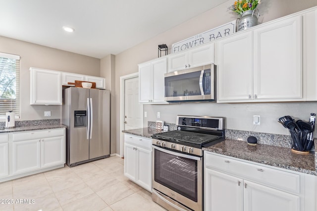 kitchen featuring stainless steel appliances, white cabinets, and dark stone counters